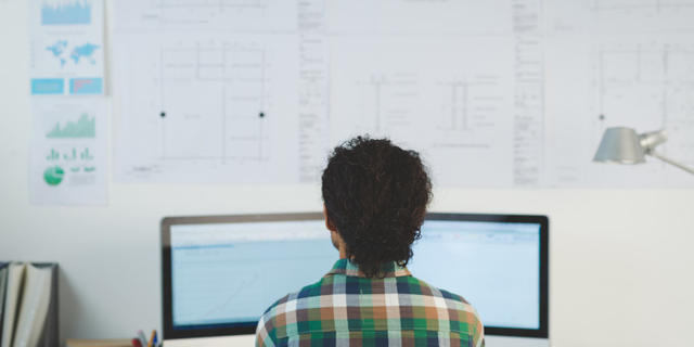 Developer sitting in front of a computer and white board