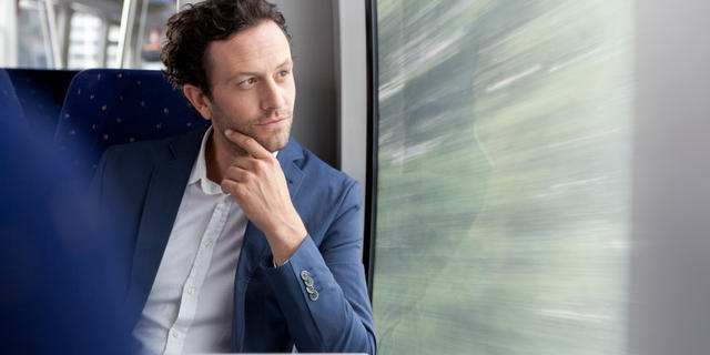 Man staring out the window of a train.